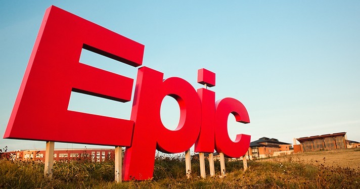 The large red Epic Systems sign on the company's campus under a clear blue sky